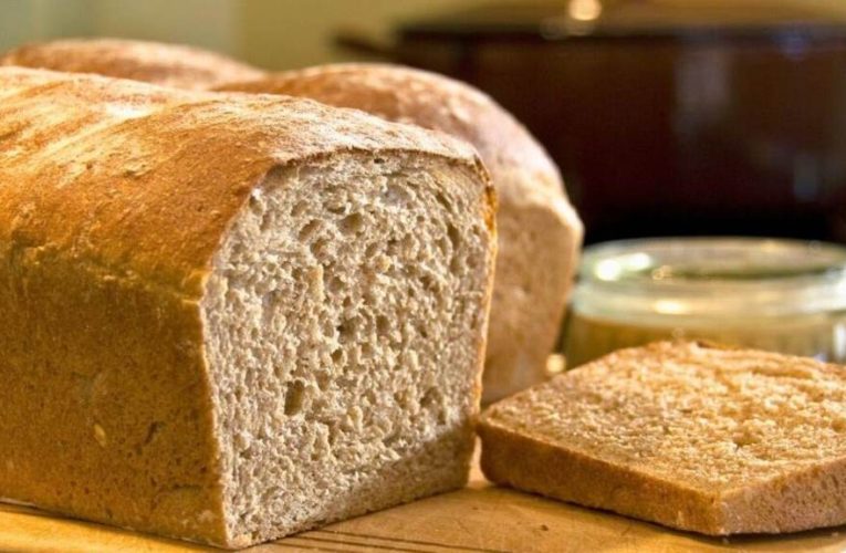 Fresh loaf in breathable cloth bag on kitchen counter.