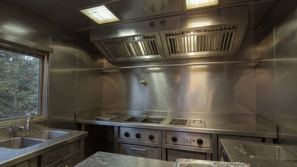 Food truck kitchen interior showing stainless steel hood with integrated fire suppression nozzles above cooking surface